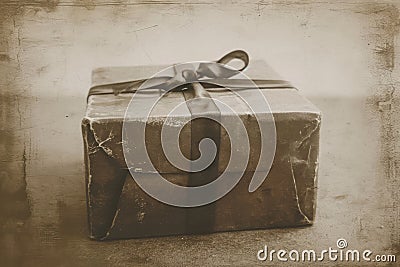 A close-up photo of a gift wrapped in brown paper, featuring a neatly tied bow on top, ready to be unwrapped, Vintage sepia tone Stock Photo