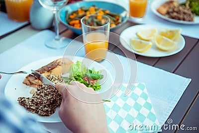 Close up photo of hands man eating salad, quinoa and fish on terrace Stock Photo