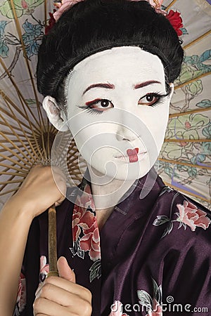 Close-up of Japanese woman with painted face holding parasol Stock Photo