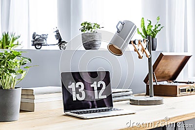 Close-up photo of laptop with clock screensaver placed on wooden Stock Photo