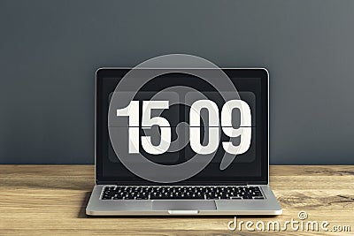 Close-up photo of laptop with time screensaver placed on wooden Stock Photo