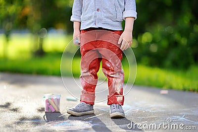 Close-up photo of little kid boy drawing with colored chalk on asphalt Stock Photo