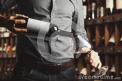 Close up photo of male sommelier pouring red wine into wineglasses. Waiter with bottle of alcohol beverage. Stock Photo