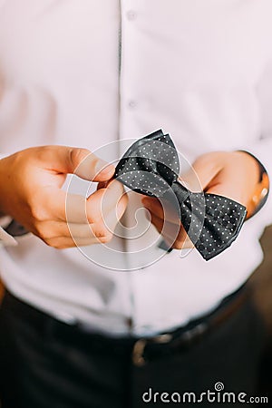 Close-up photo of man in tux holding his bowtie, two hands, no jacket Stock Photo