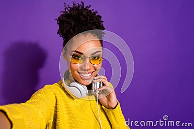 Close up photo of modern cute teen make photos moment video call have earphone yellow pullover isolated over violet Stock Photo