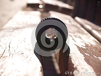 Black vintage lens lies on a wooden park bench, sun glare in reflection, sunny day Stock Photo