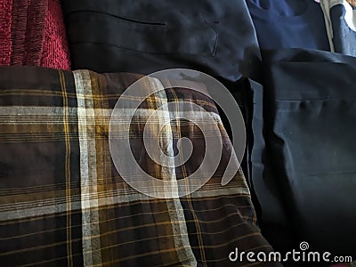 A close-up photo of a pile of clothing with someone holding a cell phone. This asset is suitable for fashion websites. Stock Photo