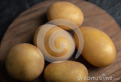 Close up photo of pile of potatoes on wooden cutting board Stock Photo