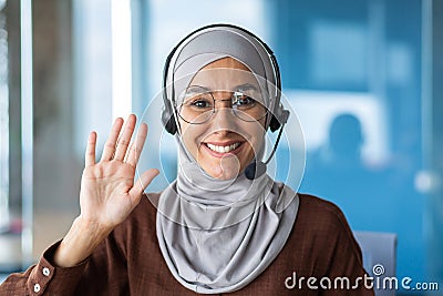 Close-up photo portrait of young beautiful Muslim business woman, tech support worker in hijab and glasses, customer Stock Photo