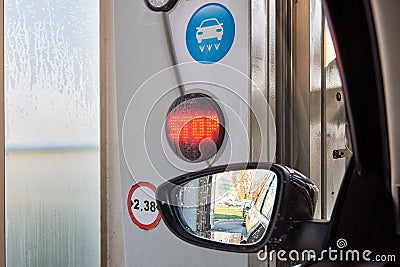 Close-up photo of a rear-view mirror inside a car wash with water drops, a symbol and a red shining STOP sign Stock Photo