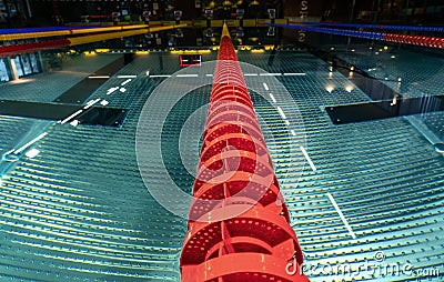 Close up photo of red lane line in empty swimming pool at night with lower light, symmetrical perspective view Stock Photo