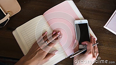 Close-up photo of scheduler notebook on a wooden table. Female hand writes on paper. Stock Photo