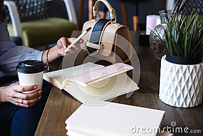 Close-up photo of scheduler notebook on a wooden table. Female hand writes on paper. Stock Photo