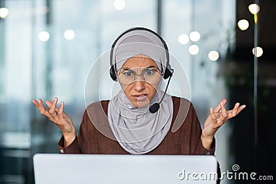 Close-up photo. Serious and strict and demanding Muslim female teacher in hijab and headset explaining and teaching Stock Photo