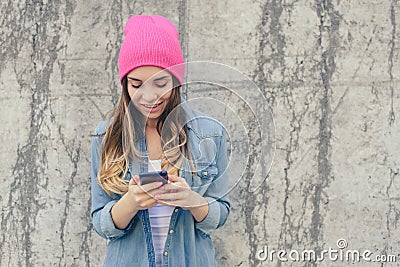 Close-up photo of smiling hipster girl reading text on smartphone. She is very happy because she got an invitation to a party cell Stock Photo