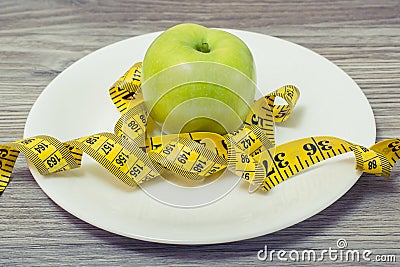 Close up photo of tape measure coiled around an apple on white p Stock Photo