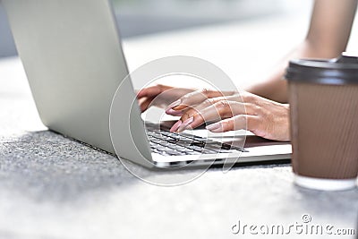 Close up photo of woman hands typing on laptop at street. Stock Photo
