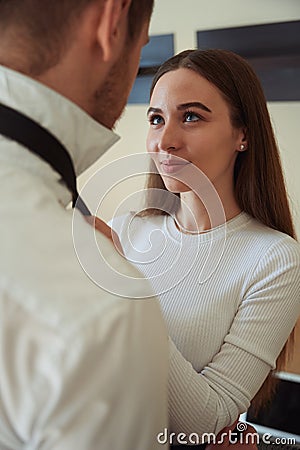 Smiling female looking at man and tying tie Stock Photo