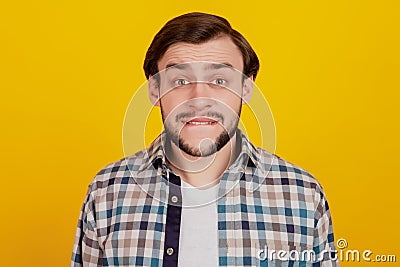 Close up photo of youn gman bite lips teeth worried fail problem checkered shirt outfit isolated yellow bright Stock Photo