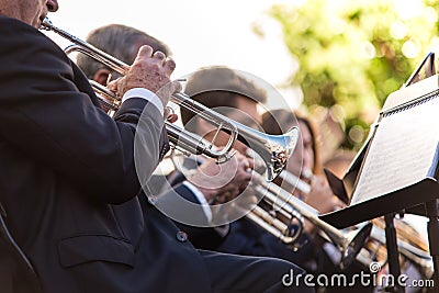 Trumpets playing in a music concert. Music sheet on the first plane and wind instruments of several musician in the background Editorial Stock Photo