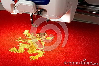 Close up picture of embroidery machine and gold lion logo on the red fabric Stock Photo