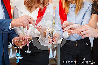 Close-up friends holding pretty Christmas sparklers on a blurred background. Sparkling bengal lights. Stock Photo