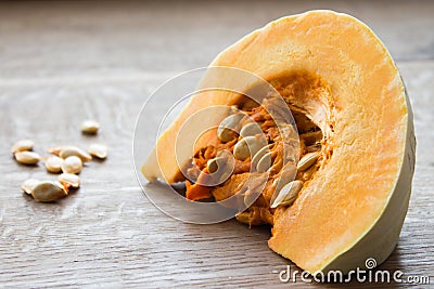 Close-up of a piece of orange pumpkin and seeds, indoors, wooden Stock Photo