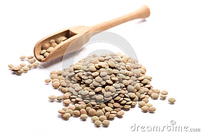 Close-up of pile of brown lentils in a wooden spoon on white background Stock Photo