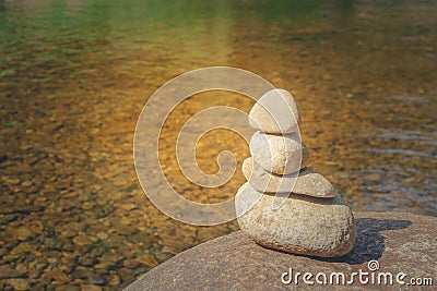 Close up pile of pebbles with clear water of river in the background. Stock Photo