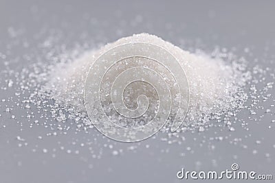 Pile of sugar crystals on grey surface, focus on heap of sweet powder to add in dishes Stock Photo