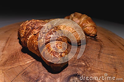 Close-up of a pile of three croissants on a wooden board against a dark background. Delicious and healthy breakfast Stock Photo