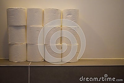 A close up of a pile of toilet paper rolls stacked in a bathroom. Toilet paper panic buying and hoarding Stock Photo