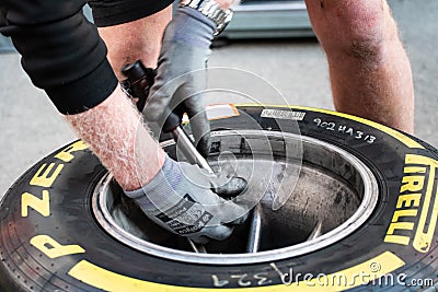 Close up of Pirelli tire and hands of Haas F1 mechanic Editorial Stock Photo
