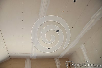 Close-up on plastering, skim coating, finishing a drywall ceiling and walls with cut holes for electrical wires with a paper Stock Photo