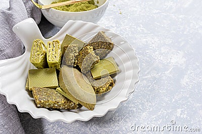 Close up plate as shell with treats containing matcha, bowl of Matcha powder,napkin on light grey background Stock Photo