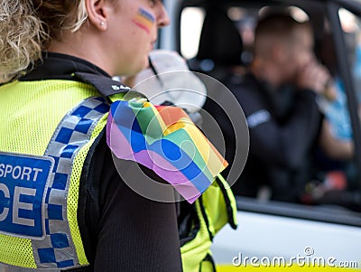 Close up police woman with rainbow colours painted on her face, and wearing a rainbow flag on her shoulder at the Gay Pride Parade Editorial Stock Photo