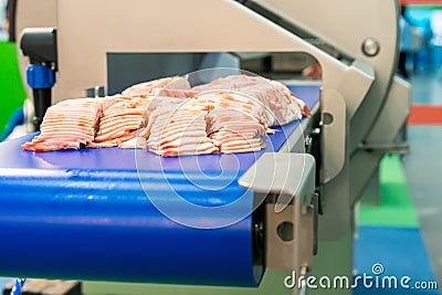 Close up pork or meat sliced on conveyor of automatic and precision slicer machine for industrial food manufacture Stock Photo