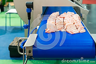 Close up pork or meat sliced on conveyor of automatic and precision slicer machine for industrial food manufacture Stock Photo