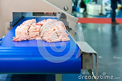 Close up pork or meat sliced on conveyor of automatic and precision slicer machine for industrial food manufacture Stock Photo