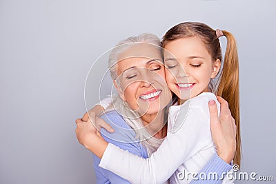 Close up portrait of adorable small lovely sweet charming beautiful girl hugging her careful attentive with white hair granny Stock Photo