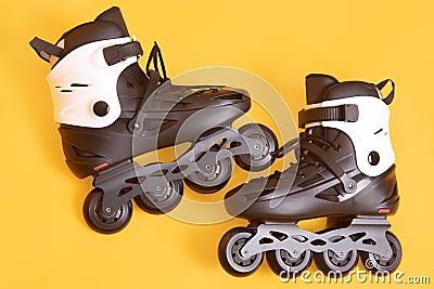 Close up portrait of adult rolling skates isolated over yellow studio background, white and black roller skates, image of pair of Stock Photo