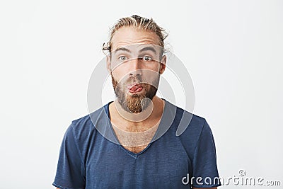 Close up portrait of attractive funny guy with stylish hairstyle and beard showing tongue and making silly expression Stock Photo