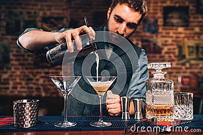 Portrait of barman pouring fancy cocktail in bar at party. Manhattan cocktail beverage in nightclub Stock Photo