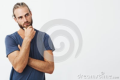 Close up portrait of beautiful bearded man with stylish hairstyle and clothes looking aside and thinking about room Stock Photo