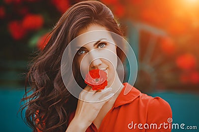 Close-up portrait of beautiful brunette woman with red rose in her lips. Toned image Stock Photo