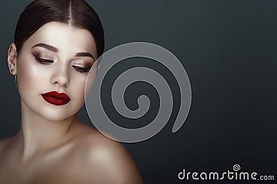 Close up portrait of beautiful dark-haired model with perfect make up and centre part sleek ponytail looking down Stock Photo