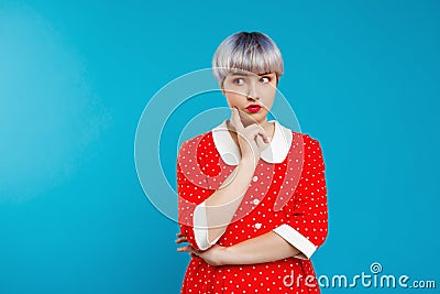 Close up portrait beautiful dollish girl with short light violet hair wearing red dress over blue background. Stock Photo