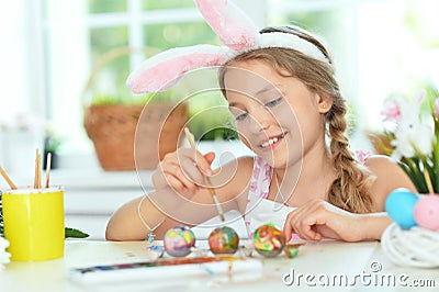 Beautiful girl in bunny ears painting eggs for Easter holiday Stock Photo
