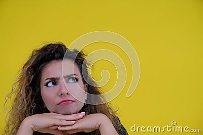 Close-up portrait of a beautiful girl on a yellow background. woman shows thoughtfulness. human emotions Stock Photo