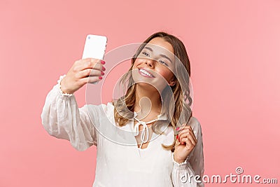 Close-up portrait of beautiful and stylish blond girl taking selfie in park at spring, gather likes and followers, make Stock Photo